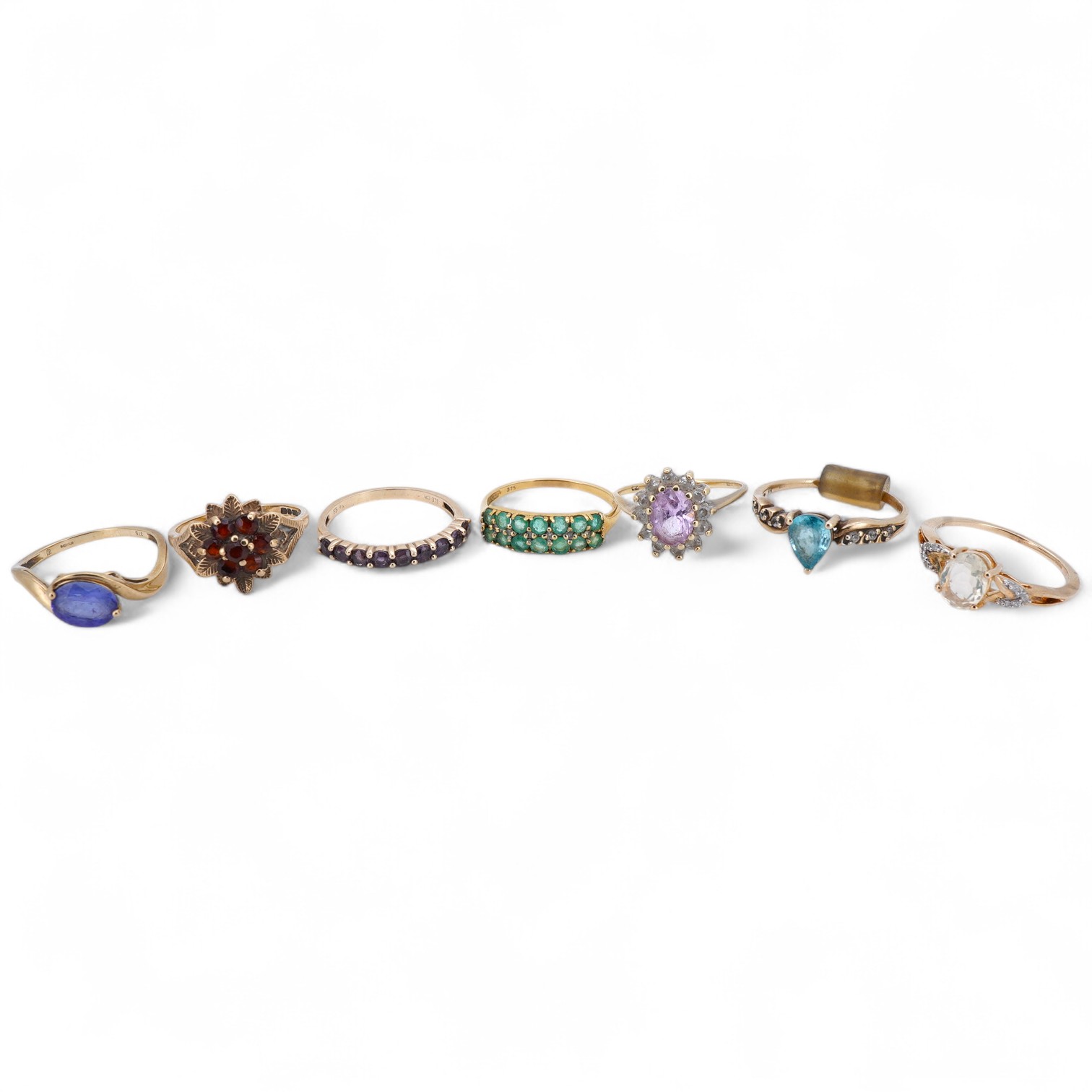 Seven gem-set rings, comprising: a faceted opal and diamond ring; a kunzite and colourless paste cluster ring; a garnet cluster ring; a blue zircon and colourless paste ring; and a tanzanite ring, all mounted in 9ct gold